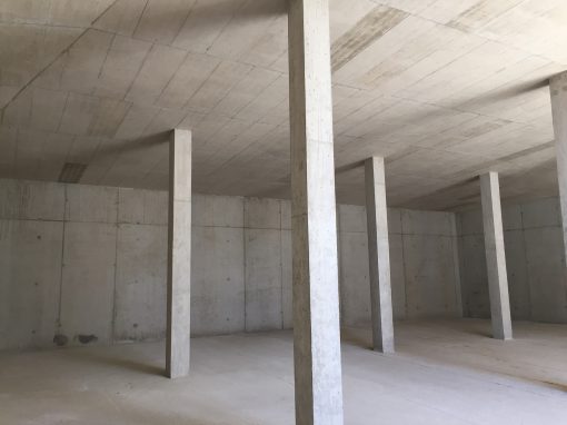Neubau-Hochbehaelter-Cadolzburg_4 Innenraum eines Rohbaus mit glatten Betonwänden, sichtbaren Deckenplatten und mehreren tragenden Betonsäulen in regelmäßiger Anordnung